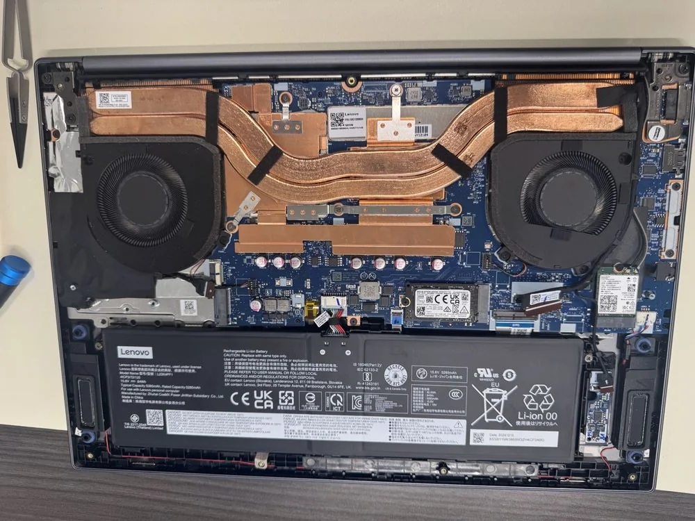 A Lenovo laptop open on our repair bench with its bottom cover off, showing the fans, board and battery