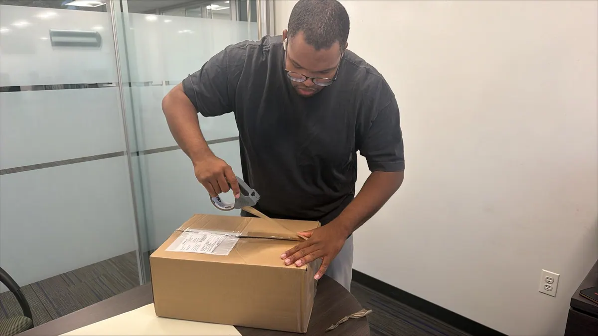 A Princeton Service Center technician sealing a shipping box with its label attached
