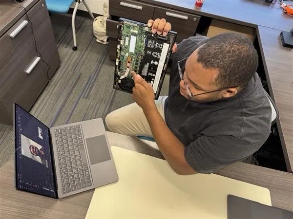 A Princeton Service Center technician showing a customer a laptop's circuit board on a video call