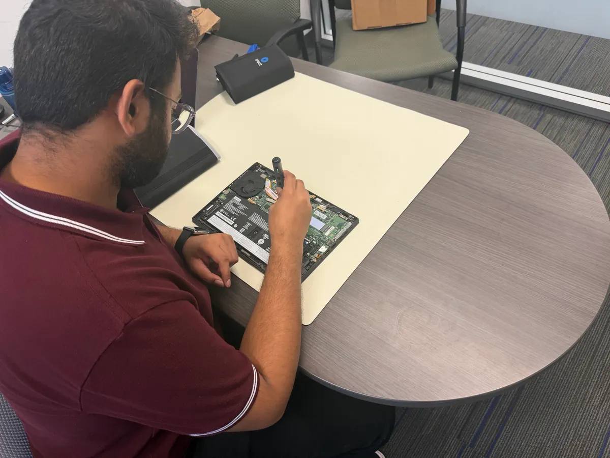 A Princeton Service Center technician working inside an opened Lenovo laptop