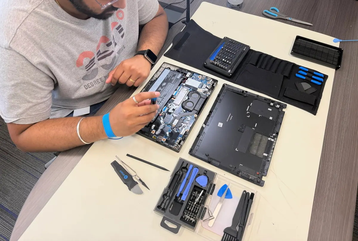 A Princeton Service Center technician repairing an opened laptop at the bench, wearing an anti-static wrist strap