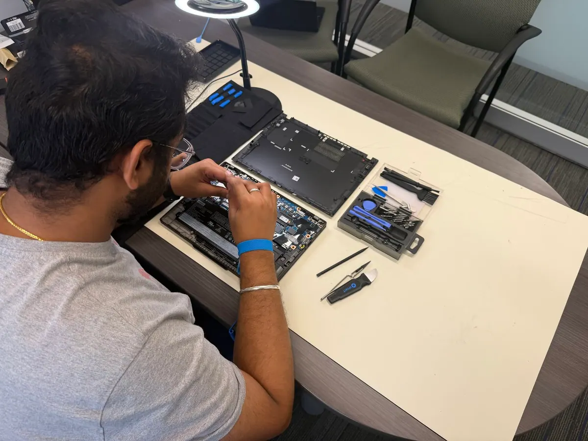 A Princeton Service Center technician working on an opened laptop at the repair bench